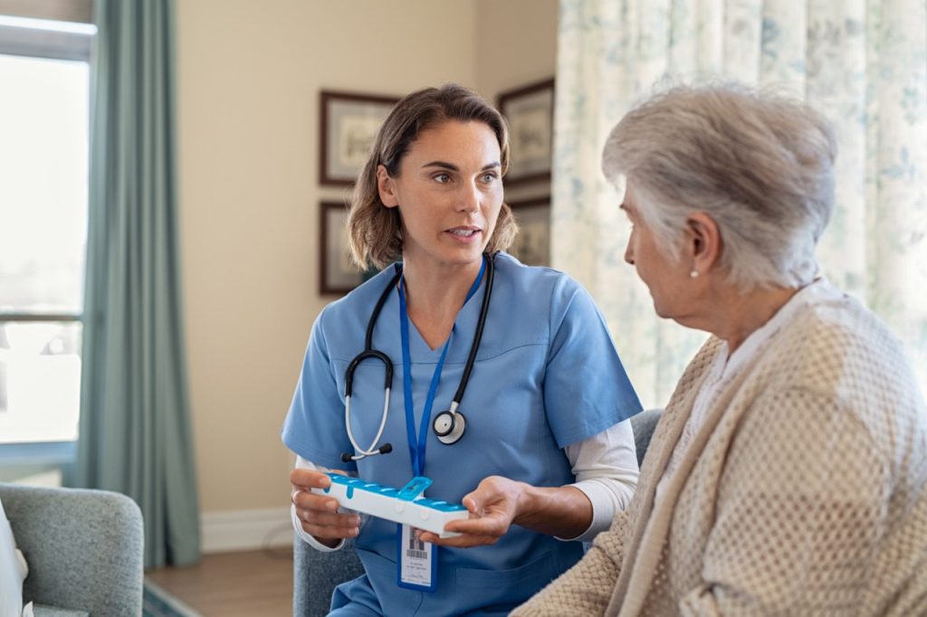 TMA nurse explaining medicine dosage to senior woman at nursing home